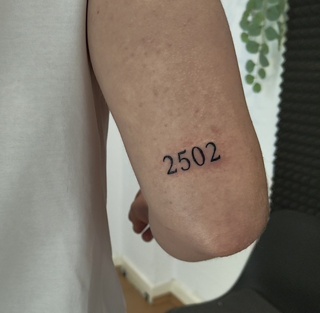 Tattoo eines Datums über dem Ellenbogen