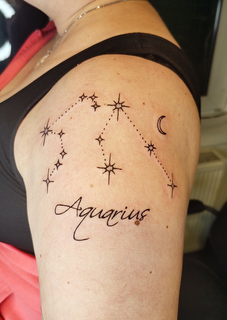 Oberarm Tatto eines Wassermann Sternzeichen mit dem Text Aquarius