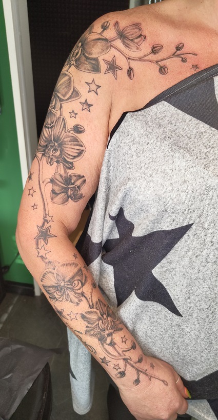 Tattoo eines Orchidee-Designs auf dem ganzen Arm. Fullsleeve Orchidee