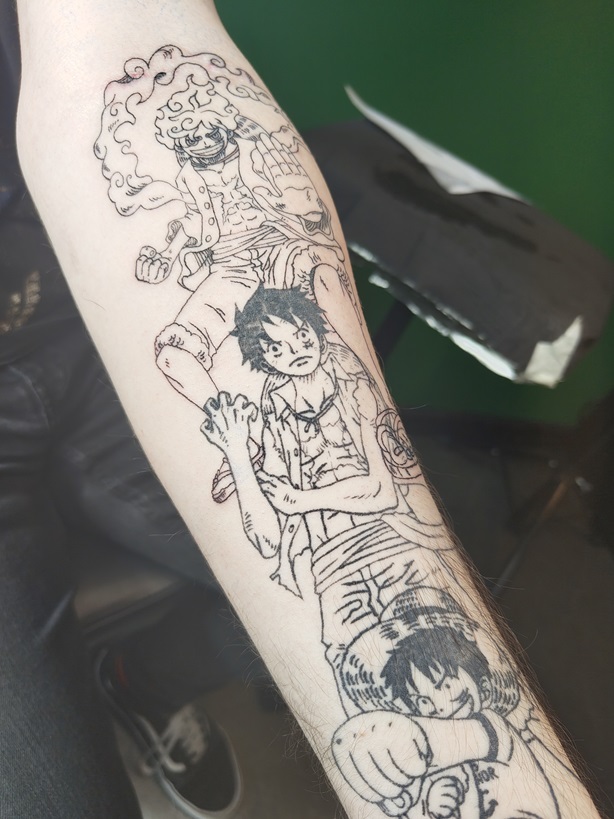Tattoo eines Anime-Motivs mit drei Entwicklungen von Ruffy aus dem Anime One Piece, Nikka-Ruffy, Timeskip Ruffy und Young Ruffy, auf dem Unterarm